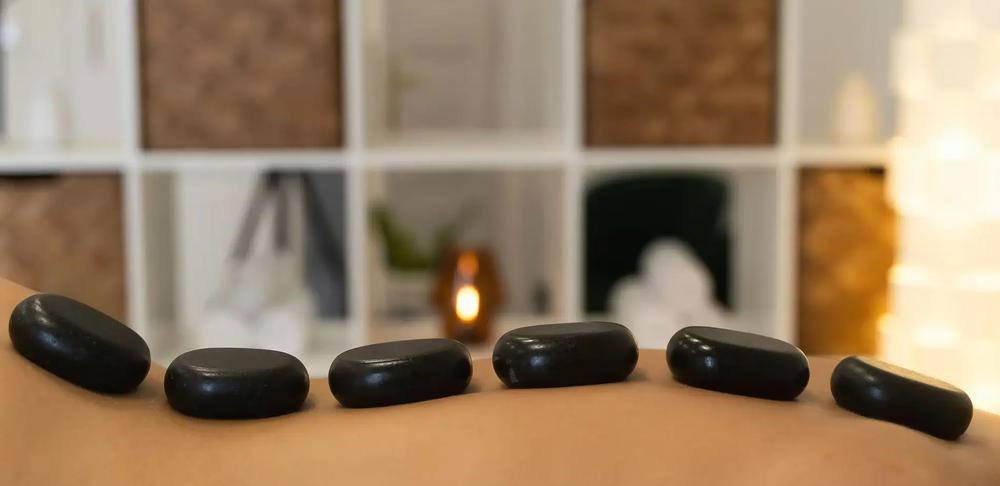 Smooth massage stones resting along a guest's back